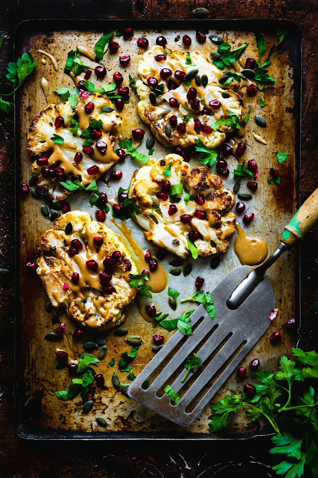 Cauliflower steaks with tahini sauce, pomegranate and flat parsley